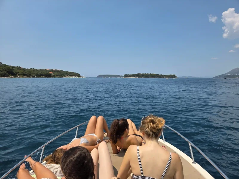 Traveler relaxing on a Dubrovnik boat, eyes closed to enjoy the sea’s sound.